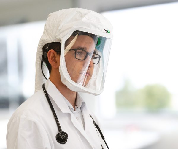 wearing a respiratory protective hood with a clear visor and air supply hose.