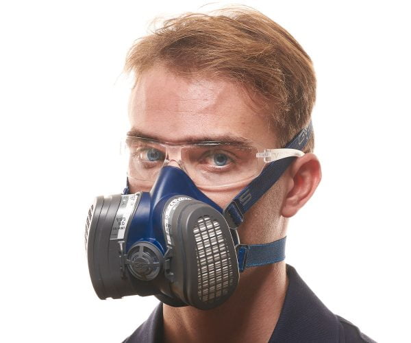 Person wearing a blue respiratory mask with dual filters and protective goggles.