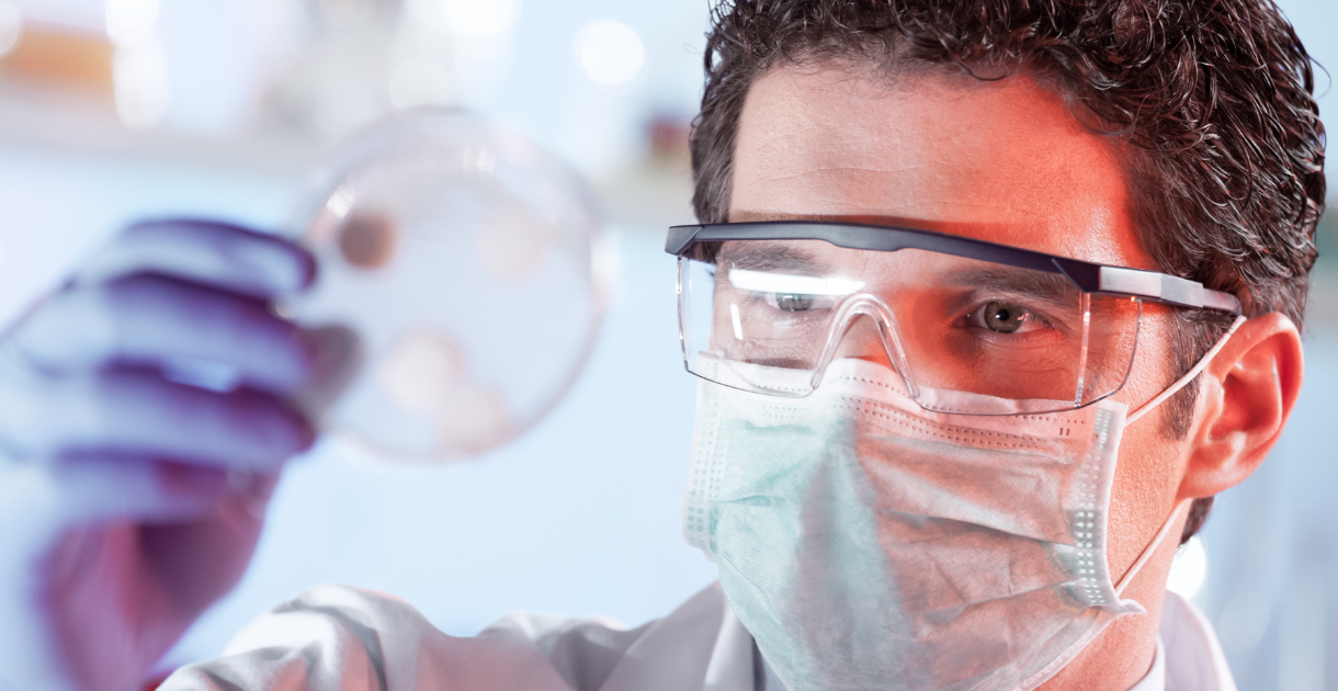 Scientist examining a petri dish, possibly testing a bacterial filter.