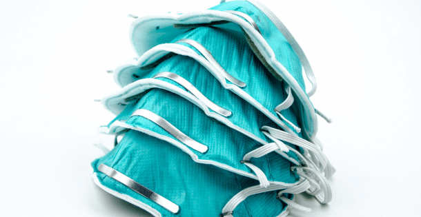 A stack of teal respirators on a white background.