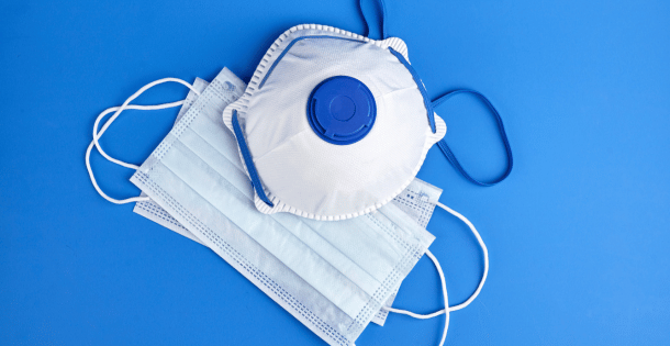 A respirator and surgical masks on a blue background.