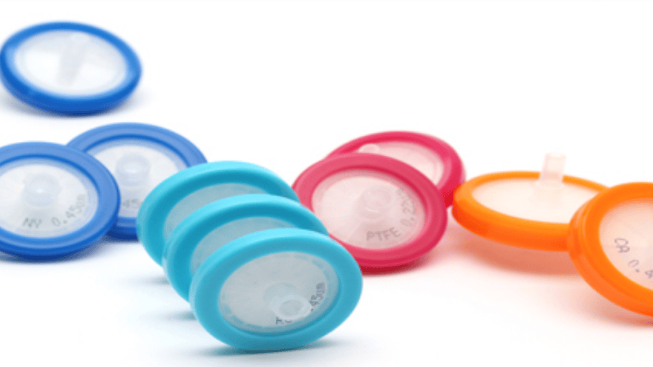 Colorful syringe filters scattered on a white background.