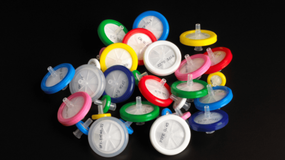 Assorted colorful syringe filters on a black background.