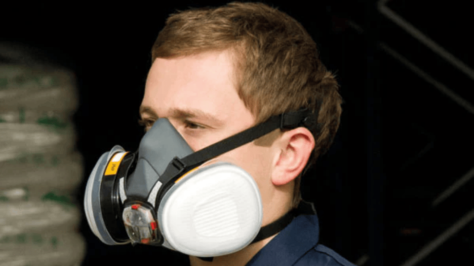 Man wearing a respirator mask with dual filters for protection.