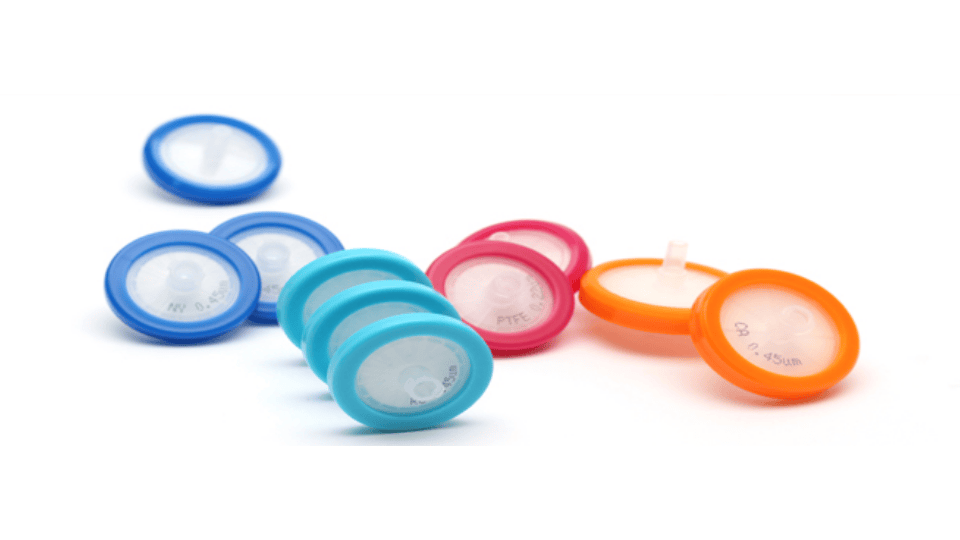 Colorful syringe filters arranged on a white surface for laboratory use.