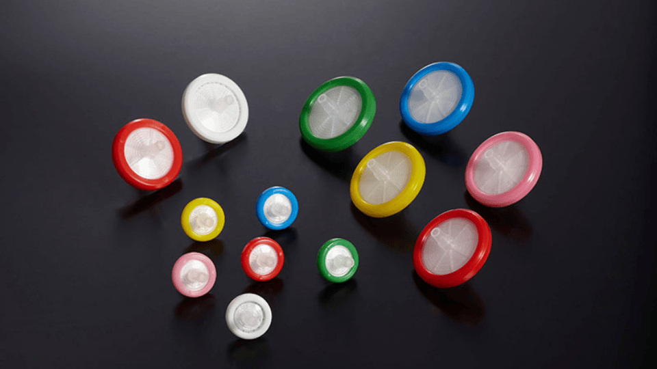 Array of colorful GVS syringe filters on a black background.