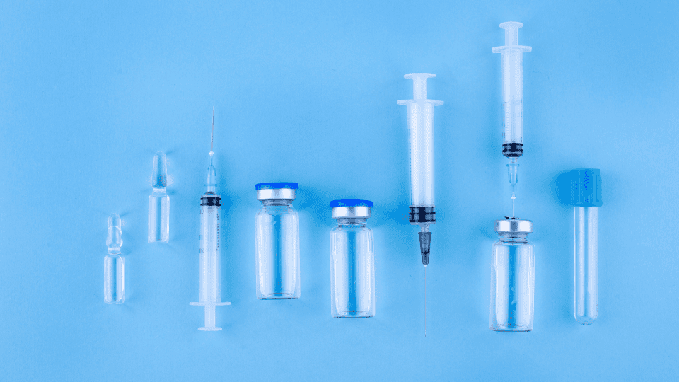 Arrangement of medical syringes and vials on a blue background, showcasing materials used in conjunction with GVS Malaysia syringe filter technology for sterile applications.